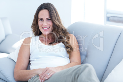 Smiling pregnant woman leaning on sofa