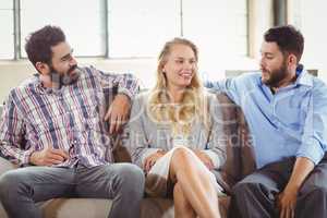 Happy business people discussing while sitting on sofa