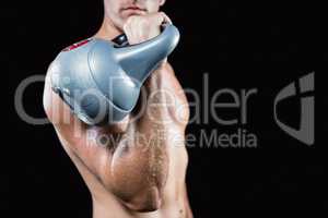 Midsection of shirtless man working out with kettlebell