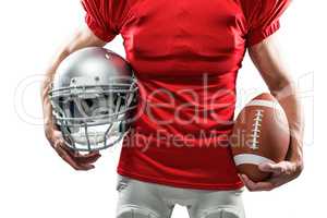 Midsection of American football player holding helmet and ball