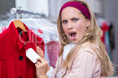 Shocked woman showing price tag to camera