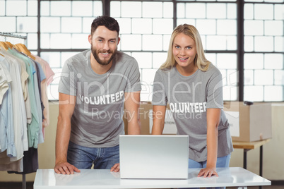 Portrait of smiling volunteers working on laptop