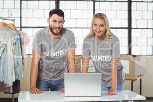 Portrait of smiling volunteers working on laptop