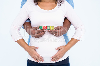 Midsection of husband with wife holding baby text