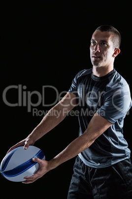 Focused rugby player looking away while holding ball