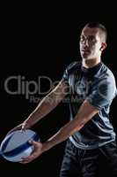 Focused rugby player looking away while holding ball