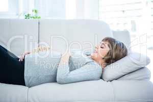 Pregnant woman playing with wooden blocks while lying on a sofa