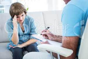 Woman looking at doctor writing on clipboard