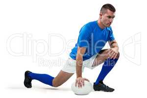 Rugby player stretching with ball