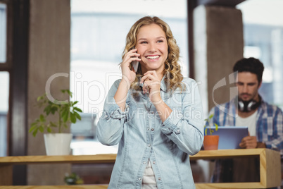 Happy businesswoman talking over phone in office