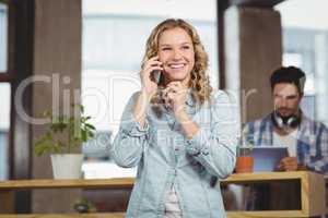 Happy businesswoman talking over phone in office