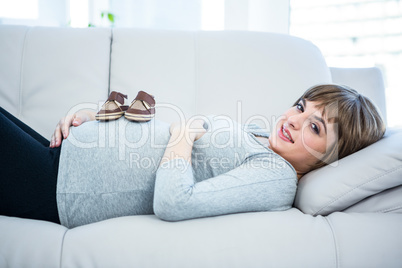 Portrait of pregnant woman with baby shoes