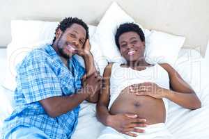 High angle portrait of smiling couple relaxing on bed