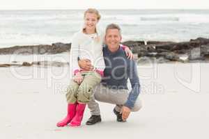 Father crouching with daughter sitting on his knee