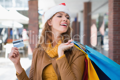 Smiling woman with santa hat and shopping bags