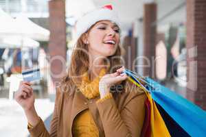 Smiling woman with santa hat and shopping bags