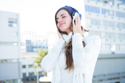 Cold brunette in warm clothes listening music