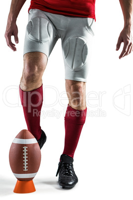 Low section of sports player kicking ball