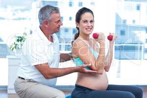 Instructor assisting cheerful pregnant woman