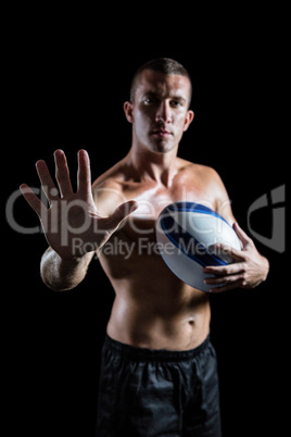 Handsome shirtless sports player showing hand while holding ball