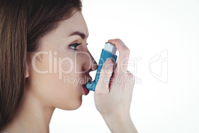Asthmatic brunette using her inhaler