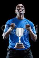 Happy athlete holding trophy looking up