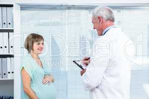 Happy pregnant woman talking with doctor