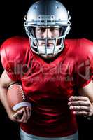 Portrait of confident American football player running while hol