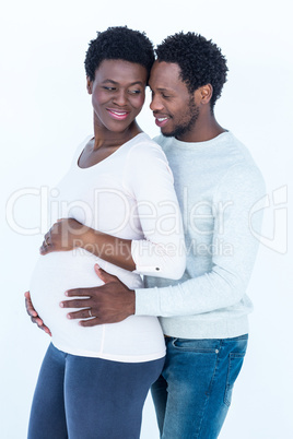 Husband touching pregnant wife belly while standing