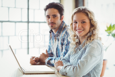 Portrait of smiling business people with laptop creative office