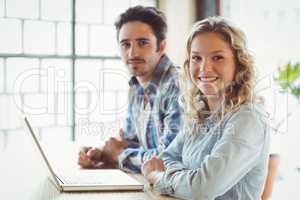 Portrait of smiling business people with laptop creative office