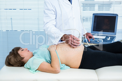 Male doctor performing ultrasound on pregnant woman