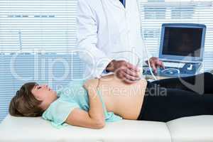 Male doctor performing ultrasound on pregnant woman