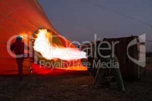 Men inflating hot air balloon before dawn