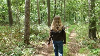 a woman goes for a walk on a forest road