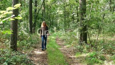 a woman goes for a walk on a forest road