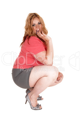 Plus size woman crouching in shorts and heels.