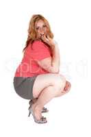 Plus size woman crouching in shorts and heels.