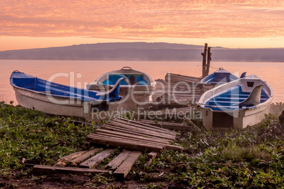 Boats moored by wooden jetty at dawn