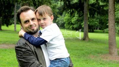 handsome dad with little son smile to camera - park