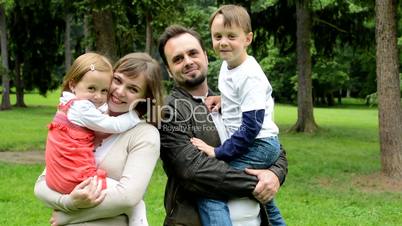 family (middle couple in love, cute girl and small boy) smile to camera in the park