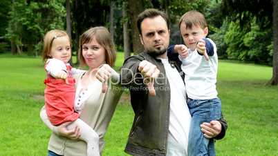 family (middle couple in love, cute girl and small boy) show thumb on disagreement in the park