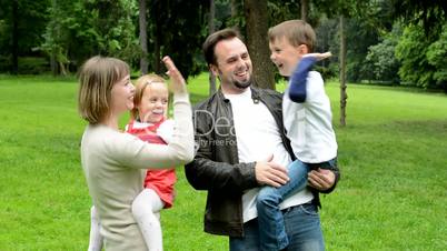 family (middle couple in love, cute girl and small boy) together give high five in the park