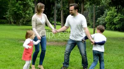 family (middle couple in love, cute girl and small boy) dance in the park