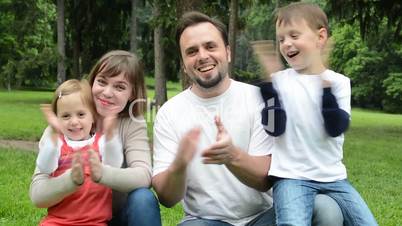 family (middle couple in love, cute girl and small boy) together clap one's hands in the park