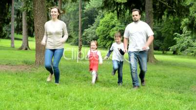 family (middle couple in love, cute girl and small boy) running in park from distance to camera