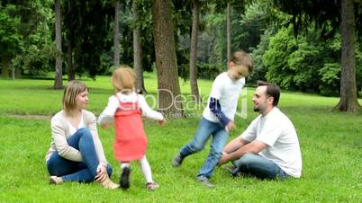 family (middle couple in love, cute girl and small boy) relax together in park - children running around parents