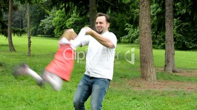 Father rotate with daughter (cute girl) around - park