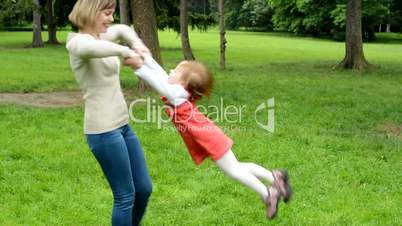 Mother rotate with daughter (cute girl) around - park