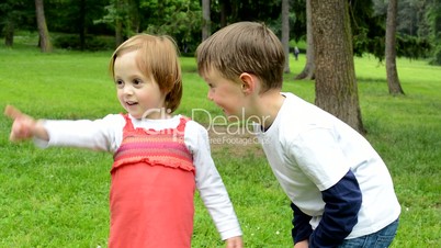 children (siblings - little boy and cute girl) talk in the park